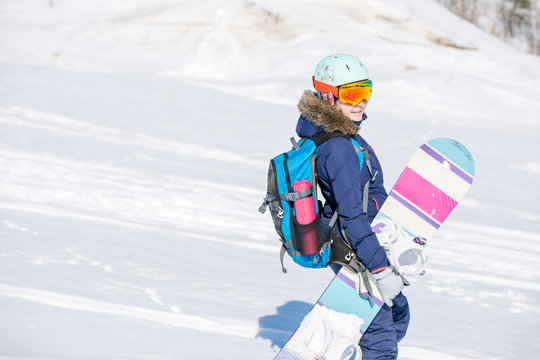 Image of female athlete wearing helmet with backpack and snowboard