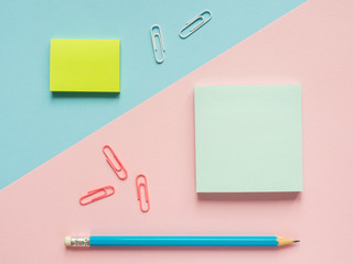 Business flat lay with copy space on a background divided in half pink and blue Notebooks to write text stickers Pencil, Stationery color paper clip.