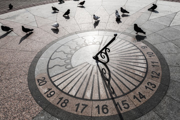 Pigeons walk on urban sundial