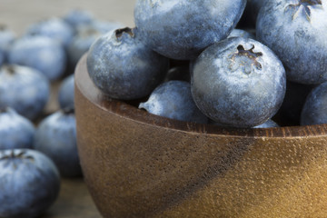 Blueberries in wooden bowl on wooden table copyspace.