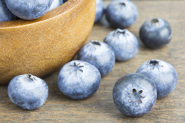 Blueberries in wooden bowl on wooden table copyspace.