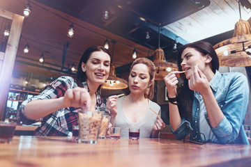 It is delicious. Joyful happy pretty woman eating French fries and chatting while sitting at the table
