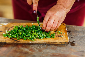 female chef cuts fresh green onion for salad