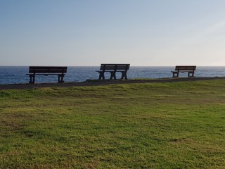 Three park benches diagonally looking out to the ocean