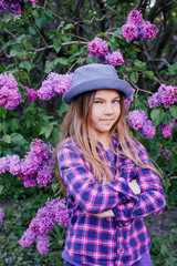 Photo of an attractive beautiful young model girl in colorful shirt with long hair in summer lilac garden