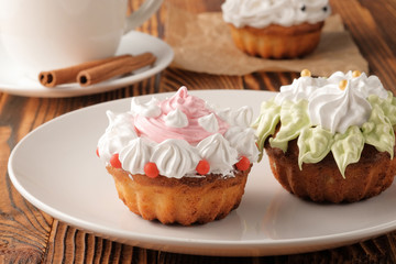 Homemade baked cupcakes on a white plate placed on a wooden table.