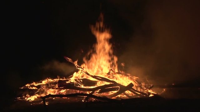 Night fire sparks flying in the dark night sky, big night bonfire in a clearing in the forest