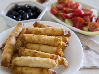 turkish cigarette patty on white plate with olive and tomato