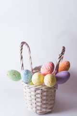 Easter eggs in a white basket on a blurry background