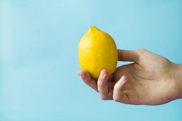 A man is holding a lemon against a blue background