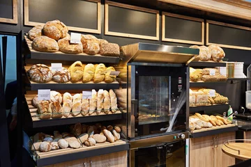 Tuinposter Fresh bread and pastries on shelves in bakery © Sergey Ryzhov