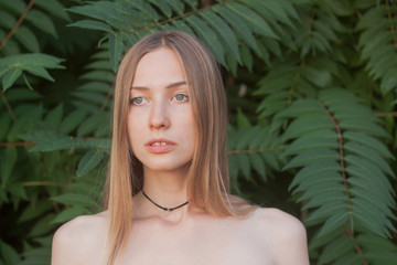 Fototapeta premium Portrait of beautiful young woman in green leaves, blonde pretty lady in spring bushes 