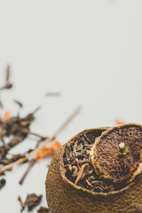 Aged Fermented Black Chinese Puer Tea in Tangerine Peel with Lid. White Background. Asian Cuisine Healthy Beverage.Close up. Copy Space. Banner Poster Streamer Template. Vintage Style Toned