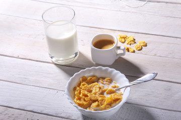 Corn Flakes cereal in a bowl, glass with milk and cap with espresso coffee. Morning breakfast.