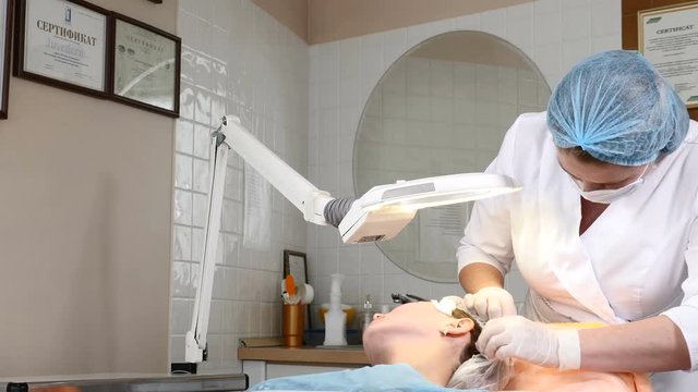 Cosmetologist prepares young female client for facial beauty procedure in heakthcare beauty centre