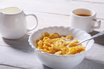 Corn Flakes cereal in a bowl, glass with milk and cap with espresso coffee. Morning breakfast.