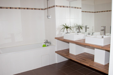 Corner of a white bathroom interior with a wooden floor a double sink and a white tub.