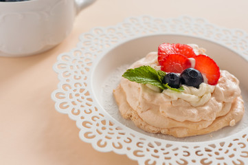 A small meringue Pavlova dessert with strawberry and mint