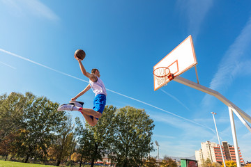 Young Basketball street player making slam dunk