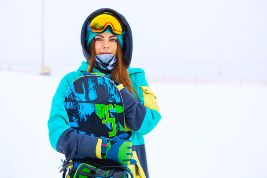 Beautiful young snowboarder girl holding snowboard.