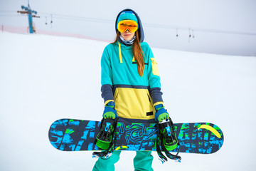 Beautiful young snowboarder girl holding snowboard.