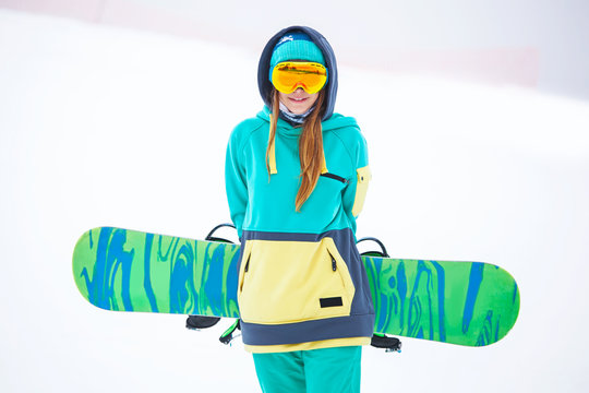 Beautiful young snowboarder girl holding snowboard.