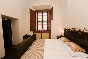 Interior of a hotel room for two, just a bed near window with flowers. room for the newlyweds