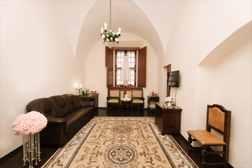 Interior of a hotel room for two, just a bed near window with flowers. room for the newlyweds