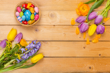 Easter background, spring flowers and colorful Easter eggs on wood