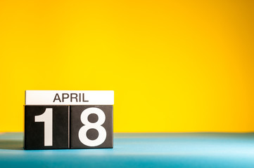 April 18th. Day 18 of april month, calendar on table with yellow background. Spring time, empty space for text