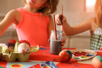 Toddlers having fun painting Easter eggs.