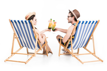 couple sitting on beach chairs and clinking with cocktail glasses, isolated on white