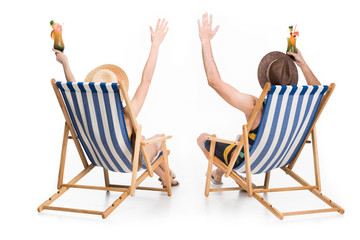 back view of couple relaxing on beach chairs with cocktails, isolated on white