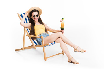 beautiful girl in sunglasses resting on beach chair with cocktail, isolated on white