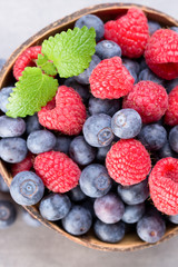 Juicy and fresh blueberries with green mint on rustic gray table.