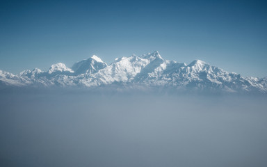 Fototapeta na wymiar The Himalayas as seen from an airplane in Nepal. Layer of clouds beneath the mountain tops. 