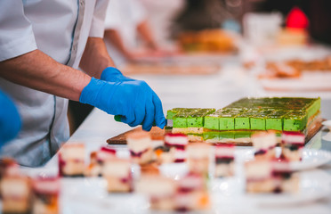 Professional confectioner cuts the cakes in confectionery