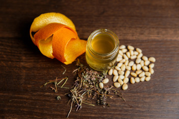 A horizontal photo of a yellow shooter alcoholic drink, garnished with orange zest, pine nuts and herbs.