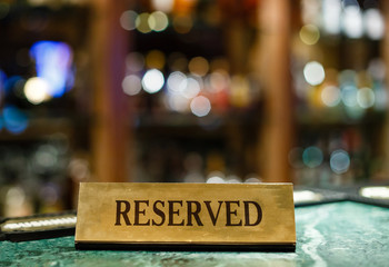 Reserved metal plate with inscription: Reserved on an arranged restaurant white table