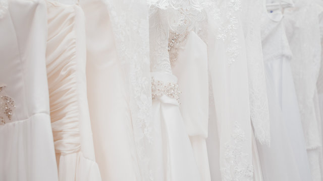Wedding dresses for bride on hangers against white background loft store. Concept wedding, engagement, attributes, clothing, love.