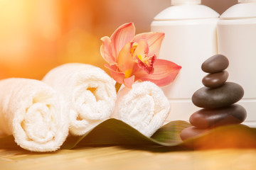 Spa background. White towels on exotic plant, beautiful orchid flower and balancing stones for relax spa massage and body treatment. Asian medicine with aroma and stone therapy for beauty healthy body