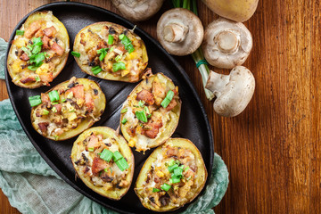 Baked potatoes in jacket stuffed with bacon, mushrooms and chees