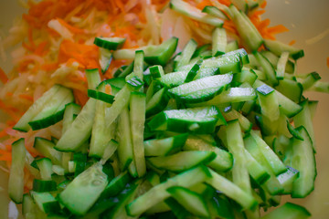 Fresh sliced salad from green ripe cucumbers and carrots with cabbage straws