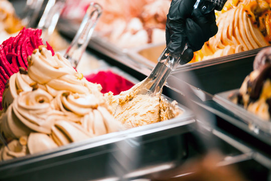 Confectioner serving ice cream from showcase fridge in confectionery