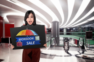 Happy asian woman holding board with Monsoon sale sign