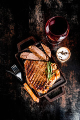 Grilled beef steak with spices on grill pan board, with and red wine glass. Copy space top view
