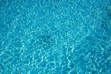 Textured light effect on the surface ripples of a blue outdoor swimming pool. Full frame background texture.