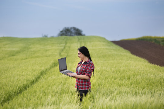 Farmer girl with laptop in field