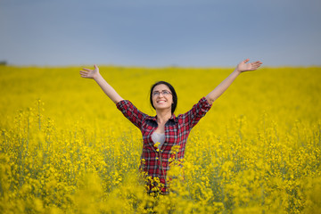 Naklejka na ściany i meble Girl with raised arms in yellow rapeseed field