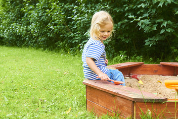 Happy little child, adorable blond child  girl having fun playing outdoors in the garden with...